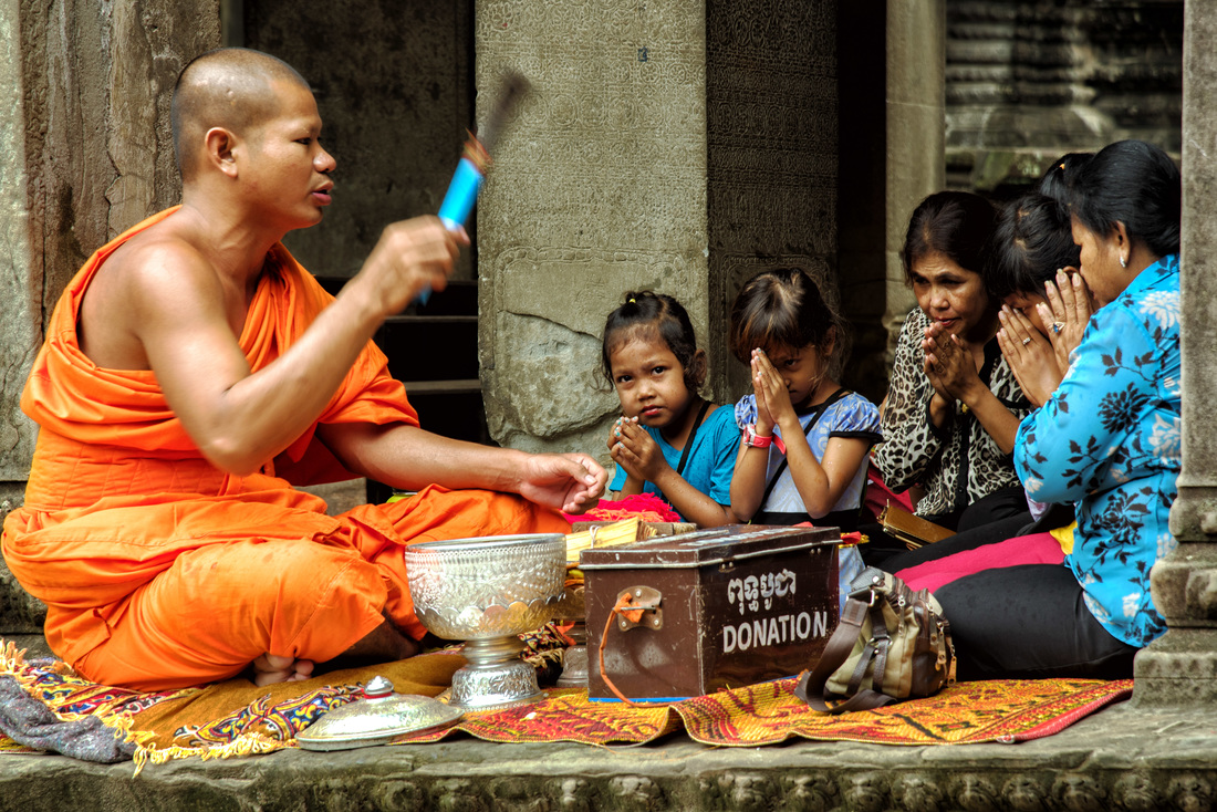 A monk prays with devotees, Angkor Wat, Siem Reap Cambodia