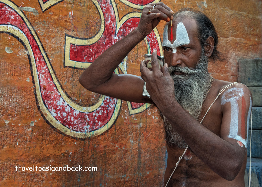 traveltoasiaandback.com - A sadu, or holy man, applies vermilion paste to his forehead 